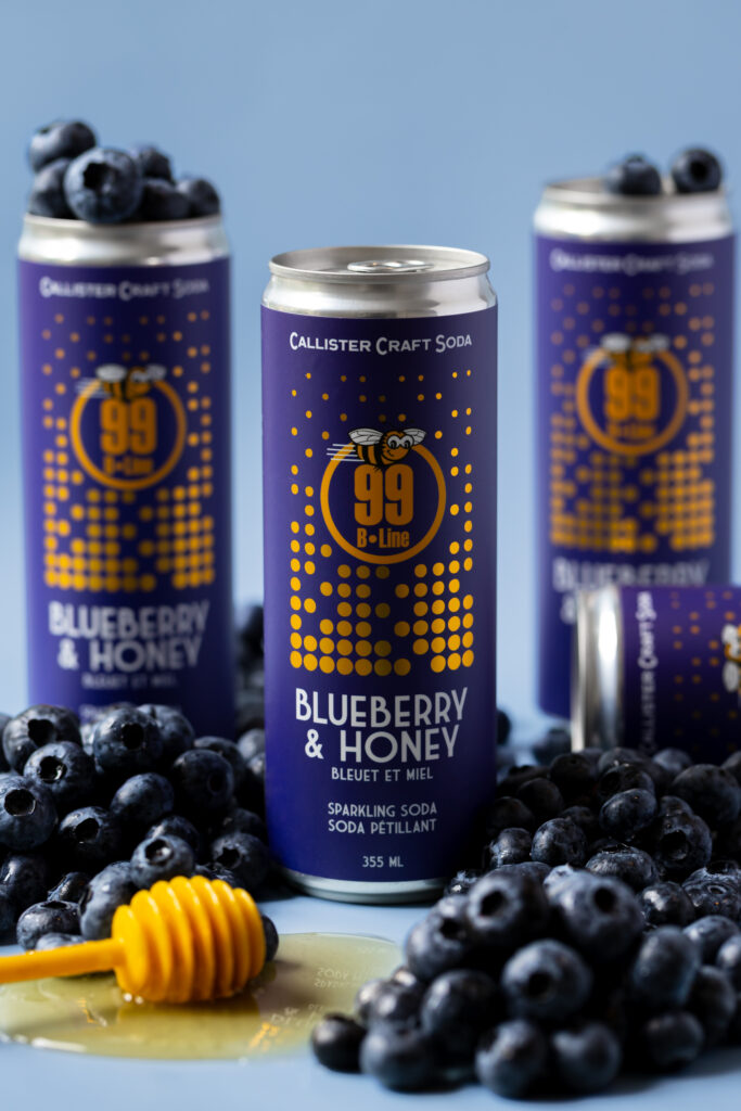 Three cans of Blueberry Honey soda with blueberries and honey
